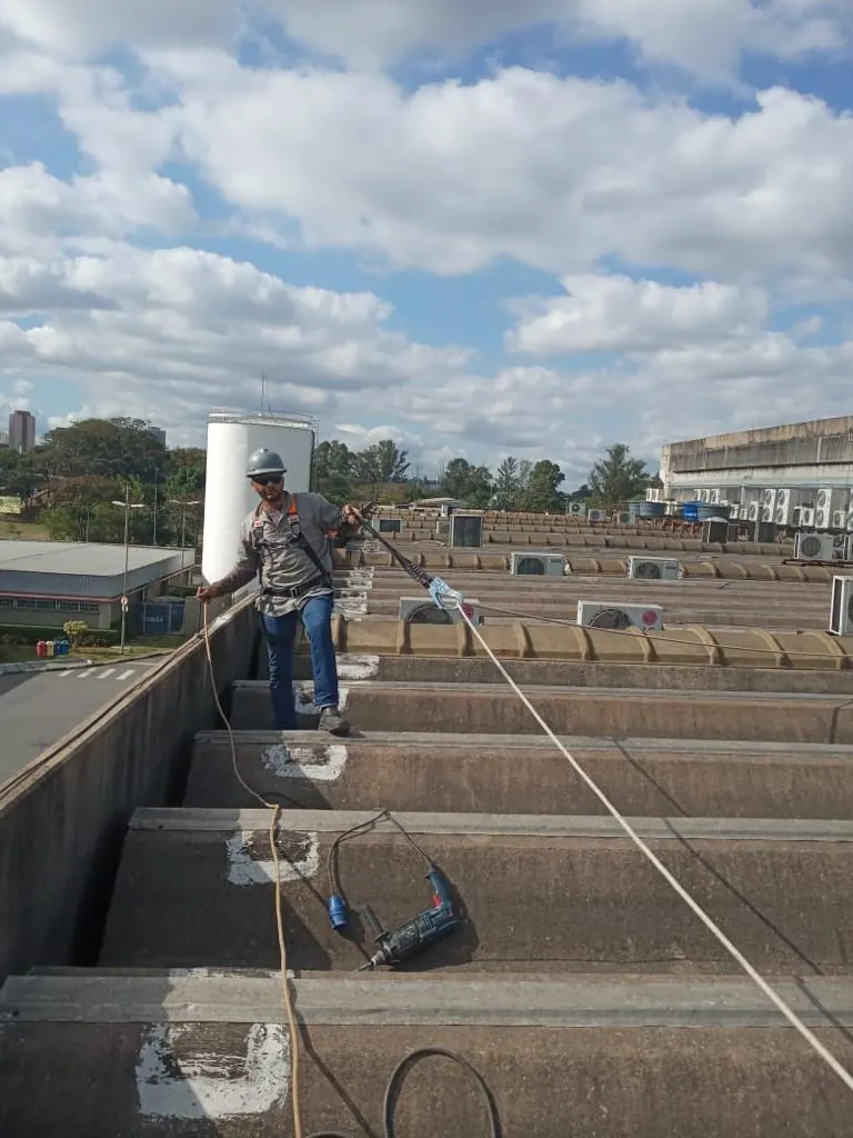 Equipe em cobertura em shed de planta industrial durante obra de reforma